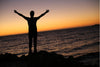 a man praying in beach at sunset